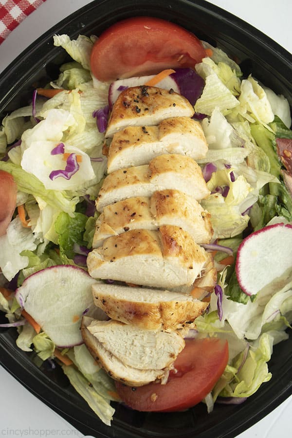 Sliced Chicken breasts on a green salad with black dish