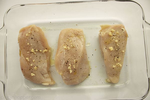 Seasoned chicken breasts uncooked in a clear baking dish