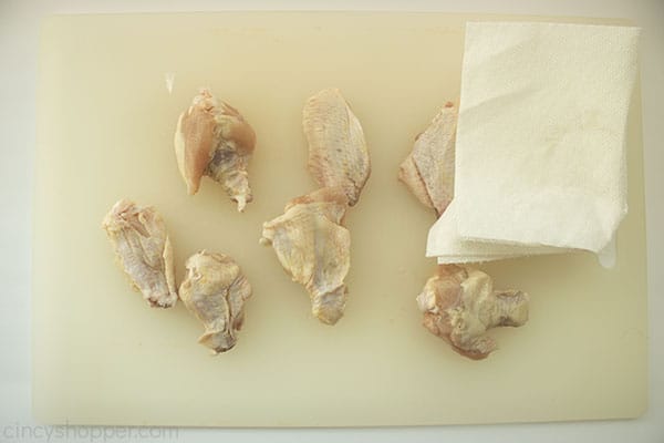 Chicken wings on a white cutting board with paper towel to pat dry