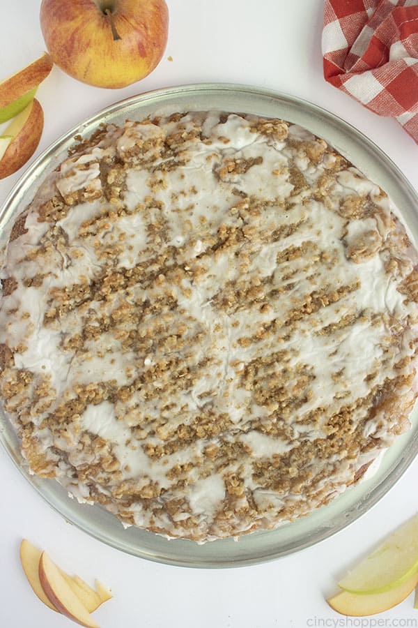 Overhead full apple dessert pizza with apple and slices on a white background. Includes red and white checkered napkin