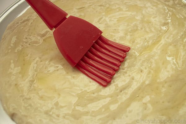Pastry brush with butter on pizza crust
