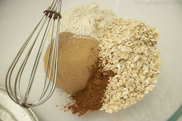 oat apple crisp topping and spices in a clear bowl with a whisk