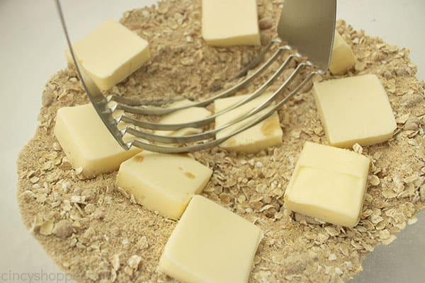 Butter added to oat topping with pastry blender in a clear bowl