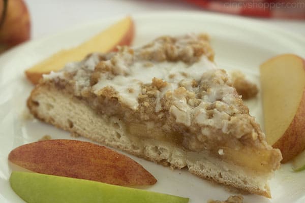 Horizontal image with slice of apple pizza on a white plate with apple slices