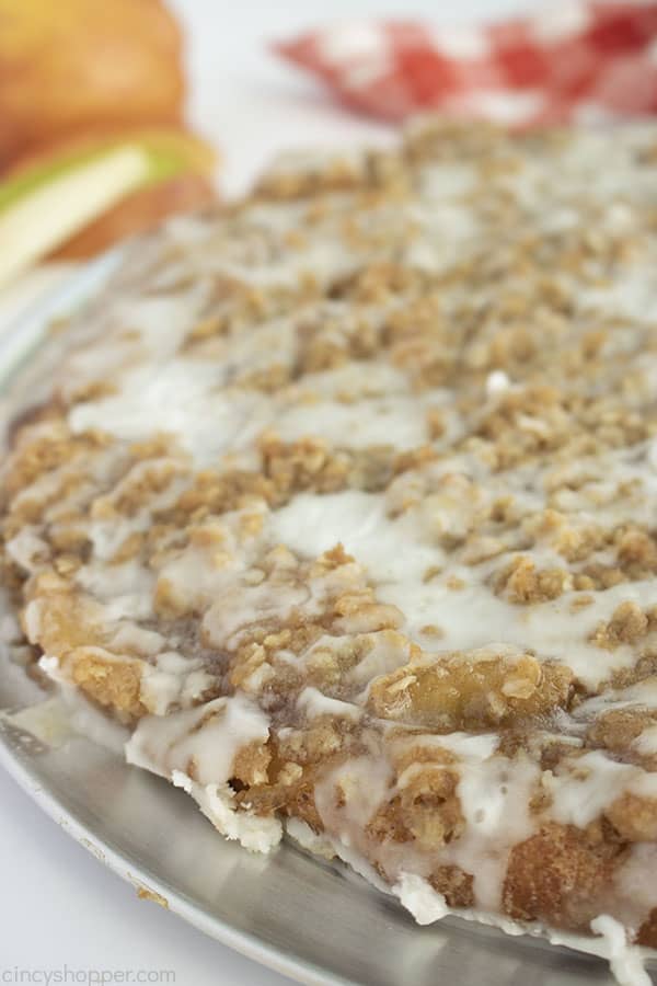 In clise shot of finished apple pie dessert pizza red and white napkin and apples in the background