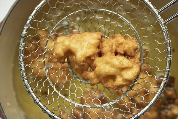 Fried apple fritter in a wire ladle 