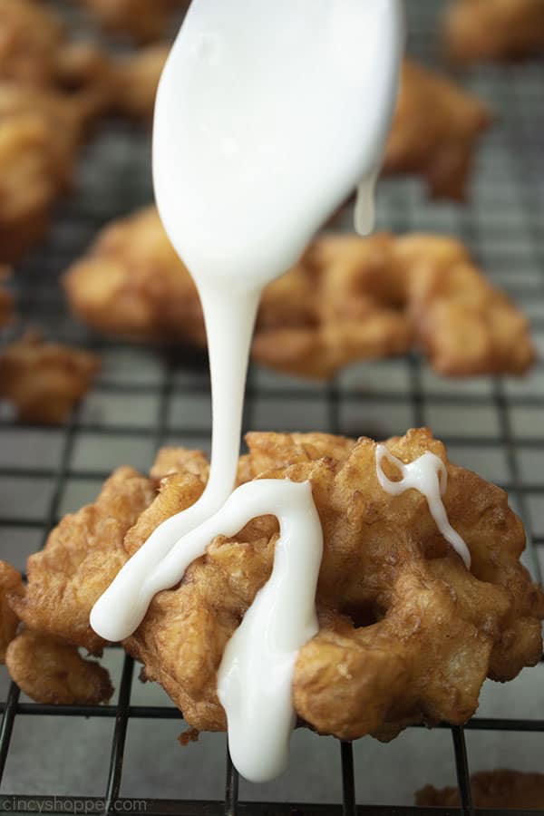 Spoon with glaze drizzling over fried fritter