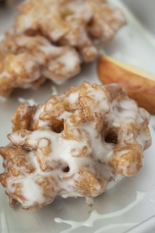 Apple donut fritter on a stainless pan with an apple slice in the background