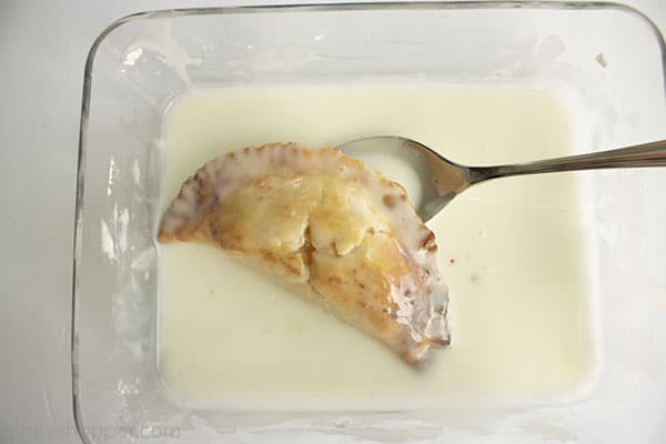 Hand pie in a clear dish with a spoon and glaze