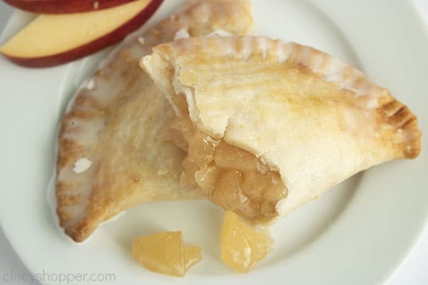 Overhead of split open hand pie on a white plate with apple slices