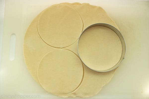 Dough on a white cutting board with round dough cutter