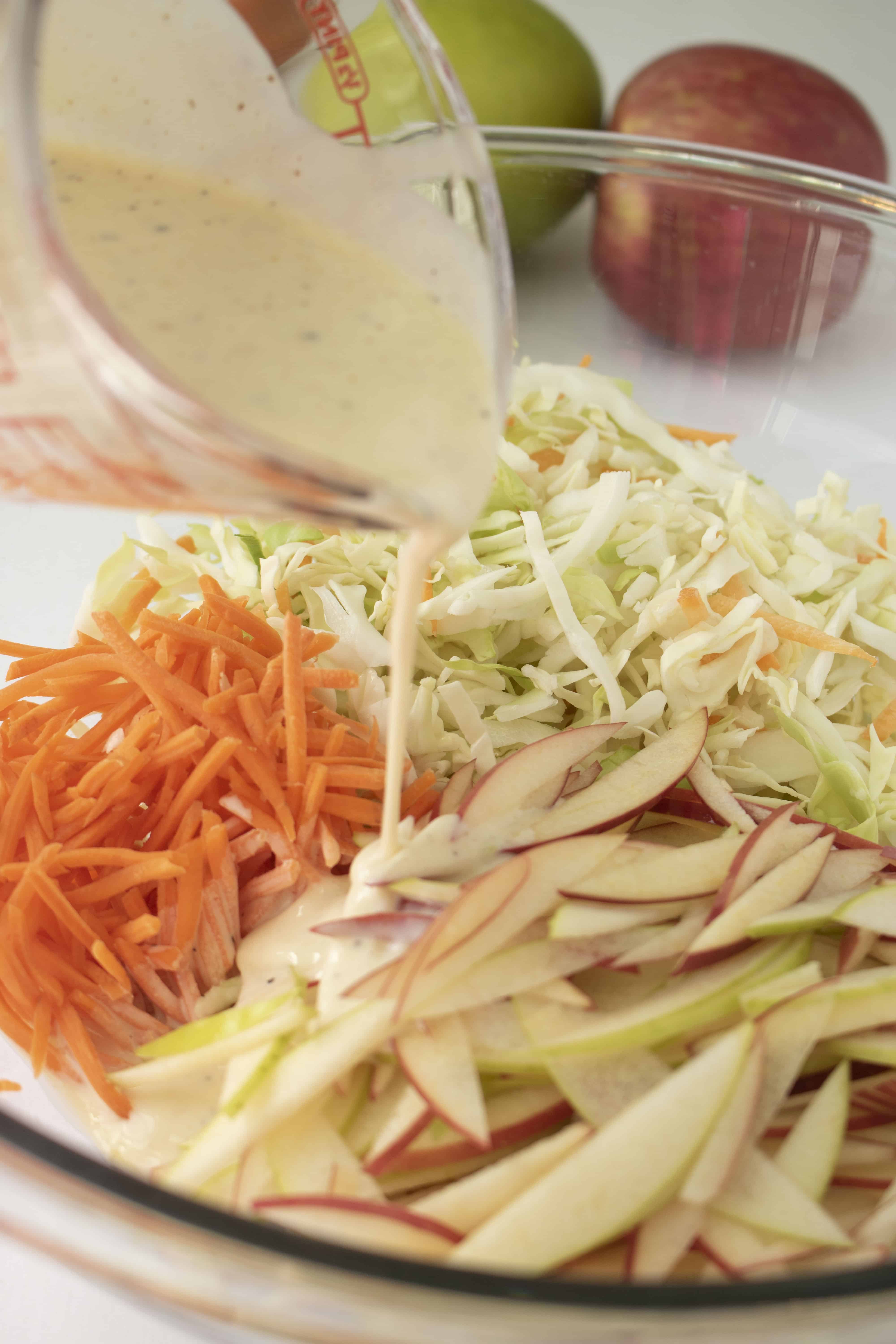 Dressing being pored onto slaw ingedients