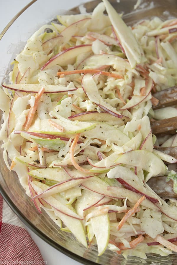 Apple slaw in a clear bowl on a white background