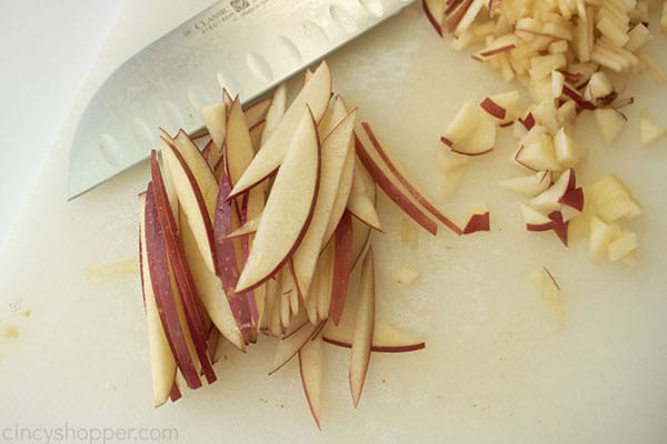 sliced apples on a white cutting board with a knife