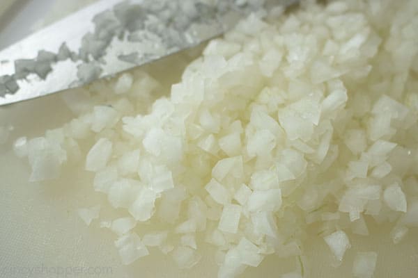 Diced onions on a white cutting board.