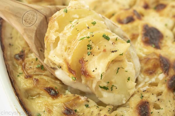 Sliced potatoes on a wooden spoon.