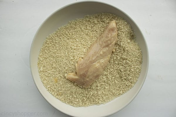 dredged chicken tender in a white bowl with panko crumbs