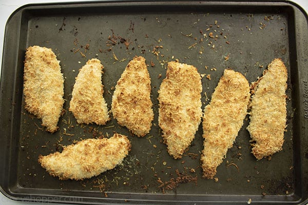 Baked crispy chicken tenders on a dark baking sheet