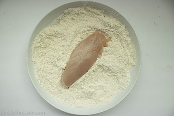 Flour spice mix in a white bowl with chicken tender