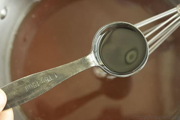 Worcestershire Sauce in a measuring spoon being added to broth gravy mixture