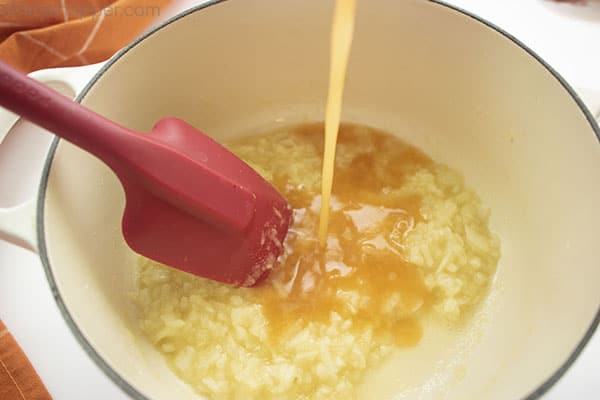 Vegetable broth added to pan with red spatula off to side