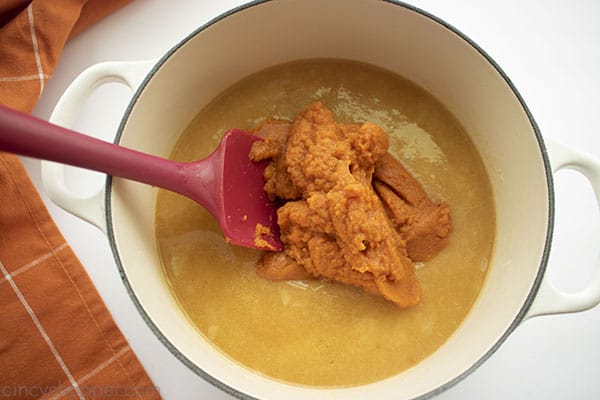 Pumpkin added to pot with red spatula 