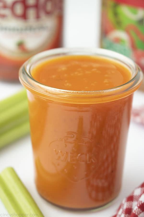 Homemade Buffalo Sauce in clear jar, white background with celery sticks Franks Red Hot and Wishbone Italian dressing