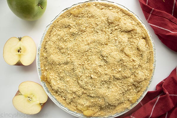 Horizontal of finished apple pie with red and green apples. Red towel in background.