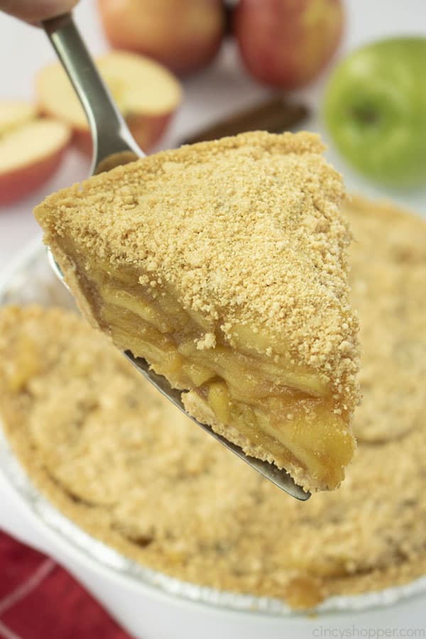 Slice of no bake Apple Pie on a pie server. Pie and apples in the background..