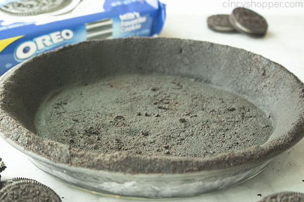 No Bake Oreo cookie crust in pie dish. Oreo cookie package and loose cookies in the white background.