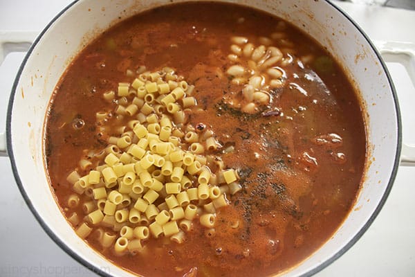 Uncooked noodles and beans added to soup pot