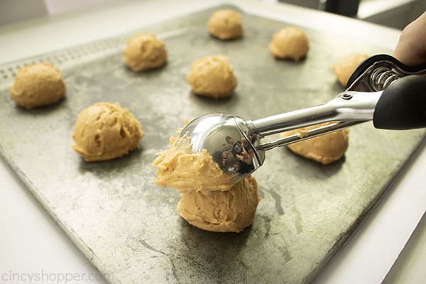 Cookie scoop adding cookie dough to a cookie sheet