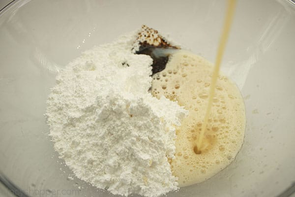 Browned butter added to dry frosting ingredients in a clear bowl