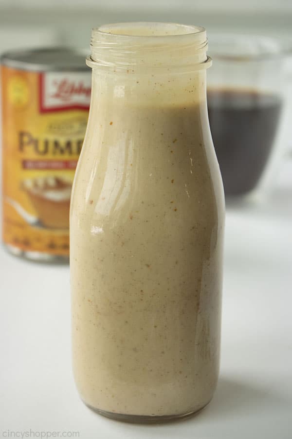 Homemade Pumpkin Spice Creamer in a clear jar. Coffee and canned pumpkin in the background.