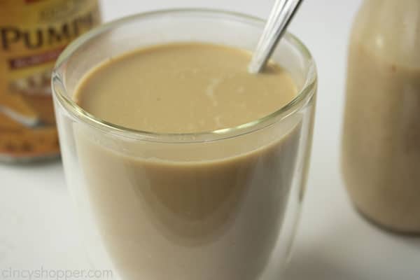 Clear coffee mug with pumpkin creamer mixed in. White background with canned pumpkin