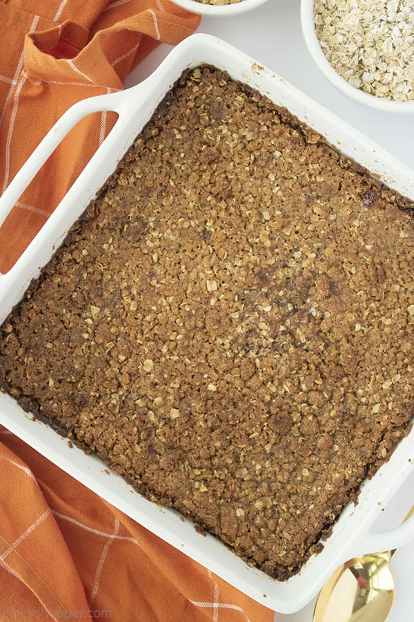 Pumpkin Crisp in a white baking dish with orange napkin and oats in the background