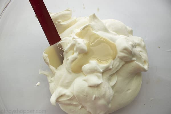 Sweetened condensed milk added to whipped cream with a red spatula
