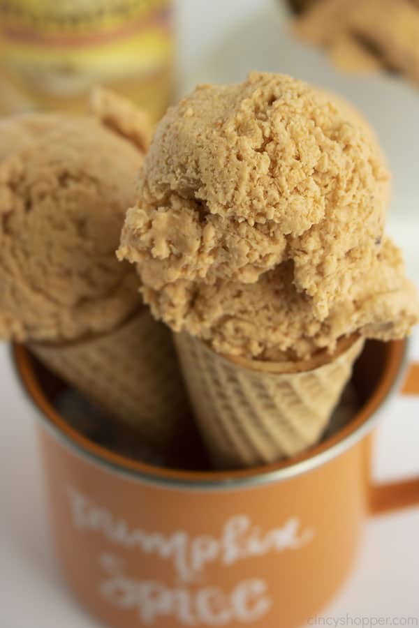 Closeup of Two pumpkin ice cream cones in a orange mug with Pumpkin Spice text