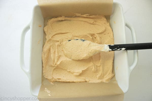 Overhead image of the mixture in a square white pan and a black baking spatula