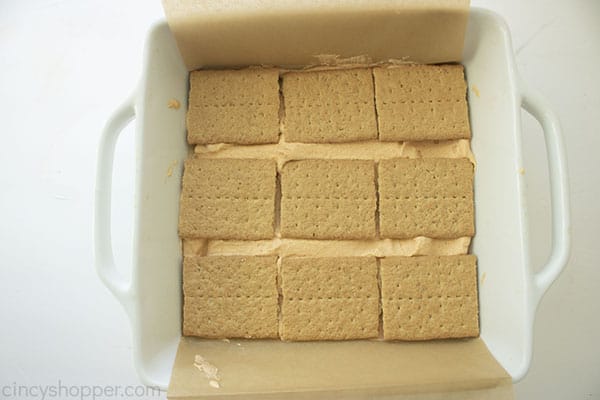Overhead image of graham cracker layer being added to the top of the mixture 