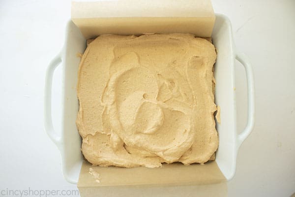 Overhead image of another layer of the whipped whipping cream pumpkin mixture being added over the graham cracker layer