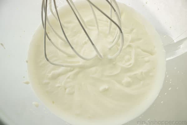 Close up image of whipped heavy whipping cream with a silver whisk 
