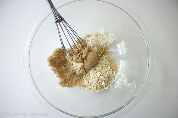 Apple crisp topping a clear bowl with whisk