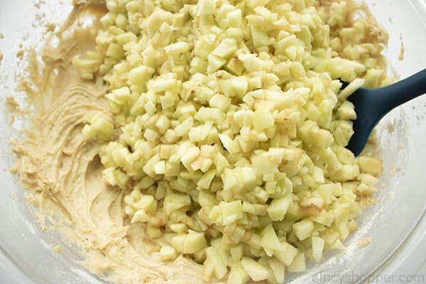 Diced apples with cake batter in large bowl.