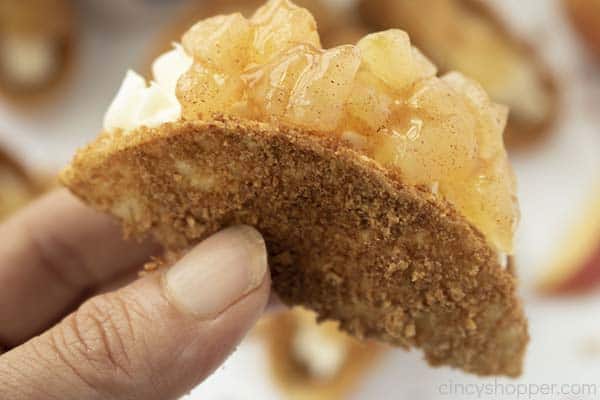 Hand holding finished dessert taco with apples