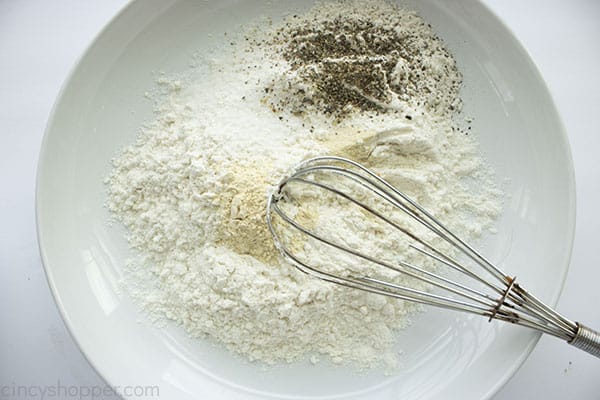 Flour and spices in a dish with whisk.