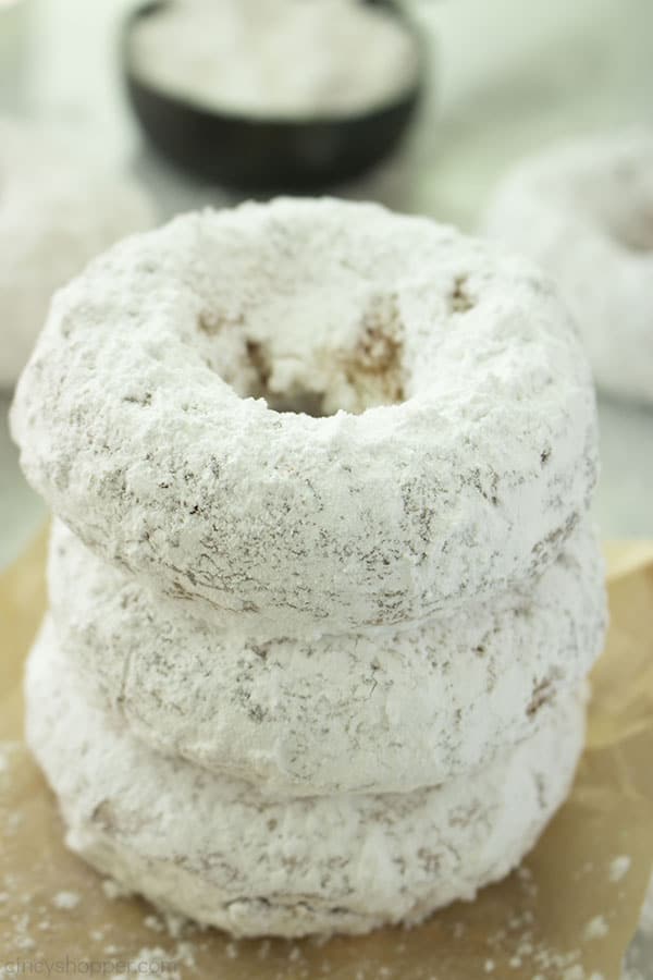 Stack of Powdered Donuts on a brown bag.