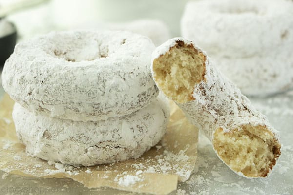 Two powdered donuts with leaning half donut