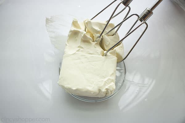 Cream cheese with beaters in a clear bowl.