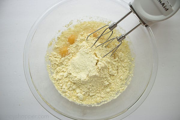 Cake mix and eggs in a clear bowl with mixer beaters